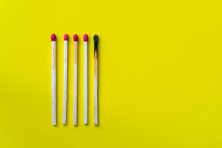 Success, defeat, achievement. The concept of happiness. Matches on yellow background. Burnt dark...