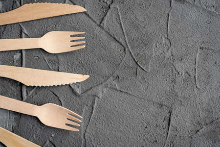 Wooden knife and fork on the black background. Eco friendly zero-waste concept. Top view with space for text Copy spaceの写真素材