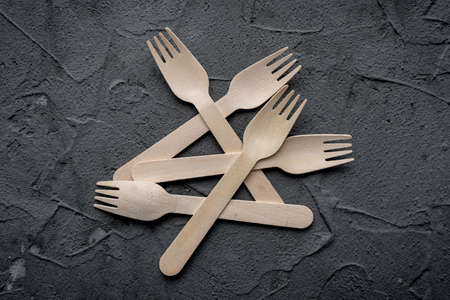 Wooden knife and fork on the black background. Eco friendly zero-waste concept. Top view with space for text Copy spaceの写真素材