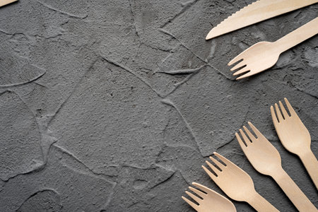 Wooden knife and fork on the black background. Eco friendly zero-waste concept. Top view with space...