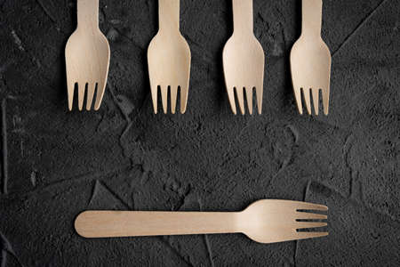Wooden knife and fork on the black background. Eco friendly zero-waste concept. Top view with space for text Copy spaceの写真素材