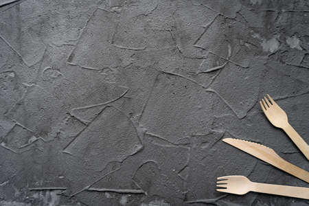 Wooden knife and fork on the black background. Eco friendly zero-waste concept. Top view with space for text Copy spaceの写真素材