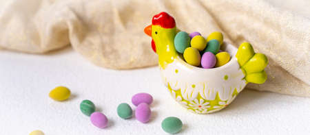 Easter concept. Mini eggs in little hen plate on white background. Color eggs pattern easter backgroundの写真素材