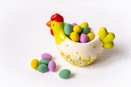 Easter concept. Mini eggs in little hen plate on white background. Color eggs pattern easter...