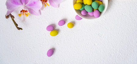 Colorful easter eggs and phalaenopsis orchid with flowers on wooden desk. Top view, horisontal....