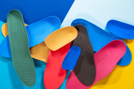 Orthopedic insoles are lined up on a wooden surface. samples of different orthopedic insoles. insoles with variety of coating.の写真素材