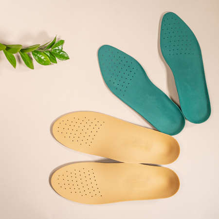 Orthopedic insoles are lined up on a wooden surface. samples of different orthopedic insoles. insoles with variety of coating.の写真素材