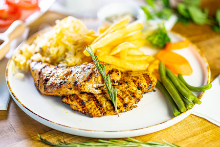 Tender grilled porterhouse or t-bone steak served with crisp golden French fries and fresh green herb salad accompanied by a BBQ or tomato sauceの写真素材