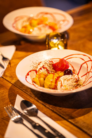 split ice cream with syrup and strawberry on white plate, side view. Chocolate, strawberry and vanilla ice cream scoops on plate, dessertの写真素材