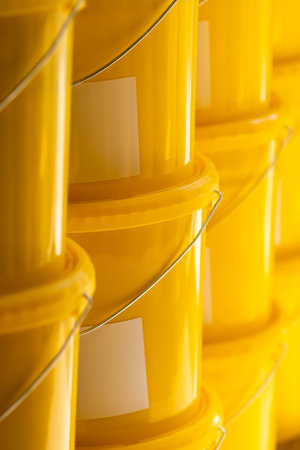 Many yellow color buckets cans in row with ink paint rowの写真素材
