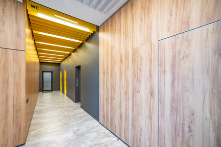 Perspective of a long corridor in office building. Doors of washrooms in hallway. Doors office with wc signs. Entrance to restrooms in a factoryの写真素材