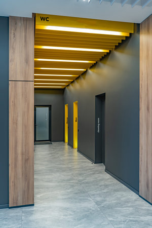 Perspective of a long corridor in office building. Doors of washrooms in hallway. Doors office with...