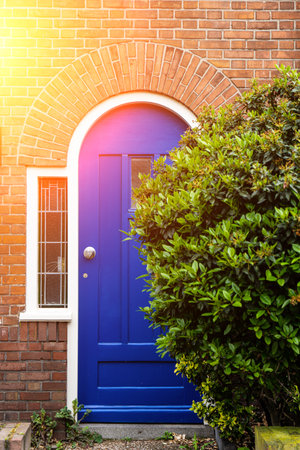 Wooden front door of a home. Front view of a wooden front door on a brick house with windows plants and a wide view of the porch and front walkway. horizontal shot.の写真素材