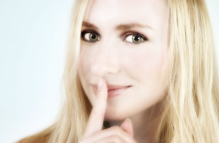beautiful blond girl closing her mouth with her fingerの写真素材