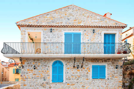Pretty stone house with blue shutters and a balconyの写真素材