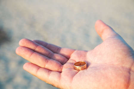 Young man holding a golden wedding band in his handの写真素材