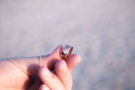 Young man holding a golden wedding band in his handの写真素材