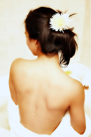 Young semi-dressed woman in a white robe, sitting with her back in the bathroomの写真素材