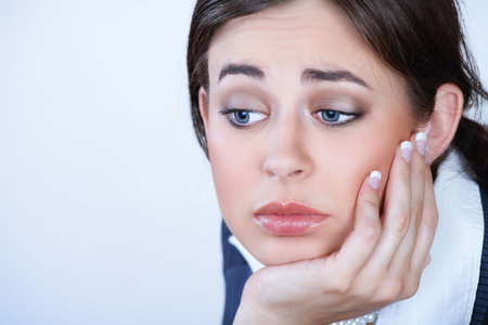very depressed  young business woman with dark hair, in her 2s, leaning on her hand 