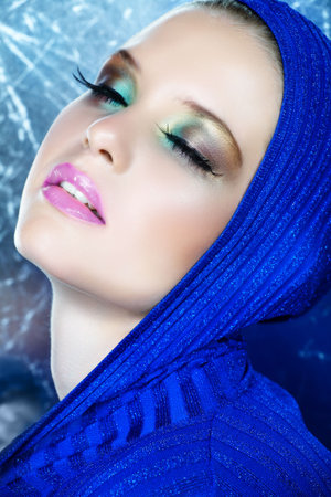 beautiful woman with long feather eyelashes in blue shiny metallic top with dreamy expressionの写真素材