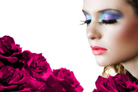 Beautiful woman with long false lashes and bright make-up on red rose background - shallow DOF, focus on the face .の写真素材