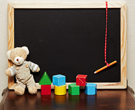 empty blackboard with a vintage generic teddy bear and old wooden blocks.の写真素材