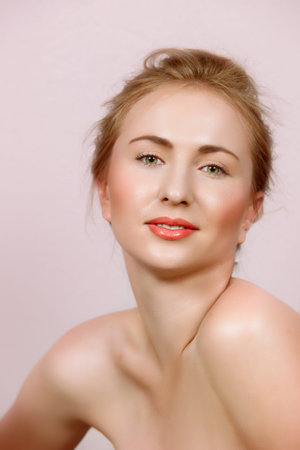 beautiful woman in with natural make-up on green eyes and coral lips on candy pink background.