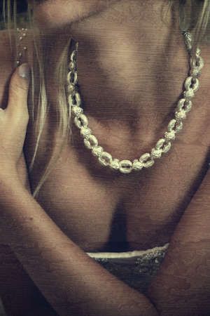 closeup of a beautiful woman in revealing corset wearing silver necklace on grunge stained backgroundの写真素材