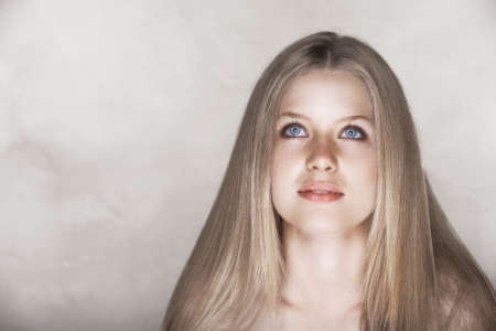 beautiful young woman with healthy long blond hair and naturally even skin texture over grunge texture wall with copy spaceの写真素材