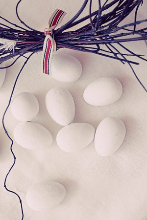 sugar coated candy eggs on handmade linen background and twigs of willow branches wreath - focus on eggsの写真素材