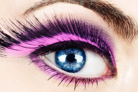 Macro of woman's eye with long pink feather fake eyelashes.