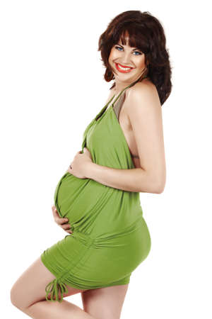 beautiful eight months pregnant brunette woman wearing green dress over white background. の写真素材