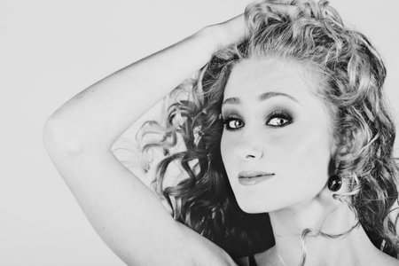 beautiful strawberry blond teenage girl with long curly hair blowing in wind over grey studio...