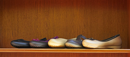 five new summer comfortable shoes in leather and rubber on display on a wooden shelf with copy space...