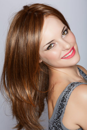 portrait of a beautiful woman with long brown hair looking over her shoulder with a smile over a...
