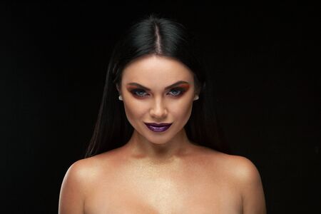 A beautiful woman in a silk top with beautiful long dark hair. Black background.Fashion, beauty, make-up, hairstyle, personal care, beauty salon, cosmetics.の写真素材