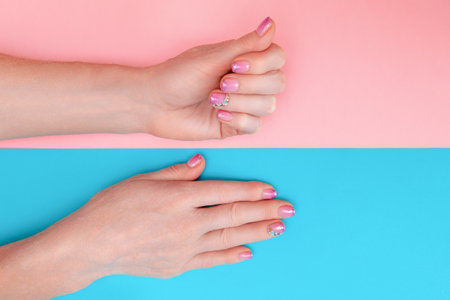 Manicure for adults. Hands of an adult woman with a beautiful manicure on a pale pink background. Hands with natural manicure at any ageの写真素材