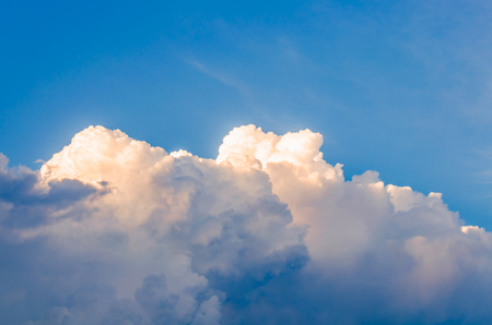 Orange and white clouds illuminated by the rising sun against the blue sky in sunny day after the rainの写真素材