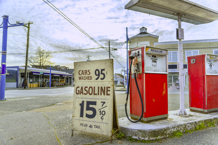 An old gas station, at the corner of the streets of the old city, with old gasoline prices, a cloudy sky and an empty street with a blurred backgroundの写真素材