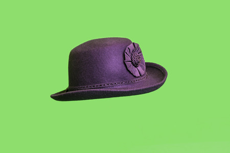 Garment, dark female felt hat made of wool, with a flower of cloth, isolated on a green background.の写真素材