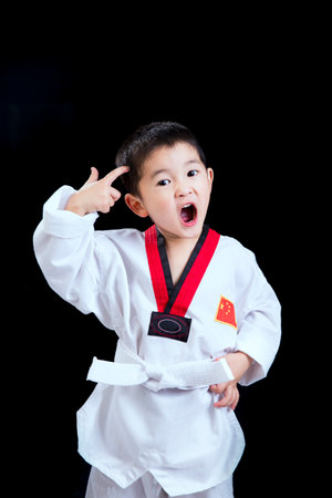 Asian boy in kimono and taekwondo uniform on black backgroundの写真素材