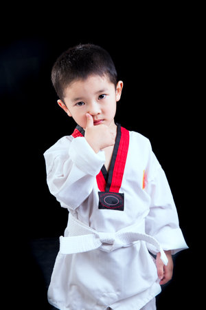 Asian boy practicing taekwondo isolated on black background (black)の写真素材