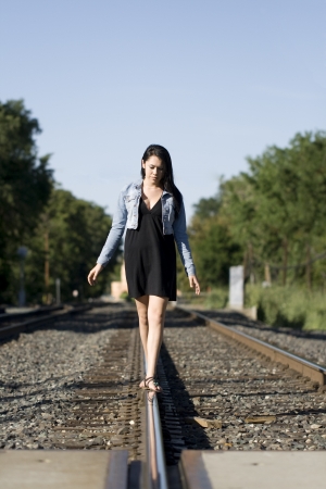 Pretty teen walking alone on train tracks on a beautiful dayの写真素材