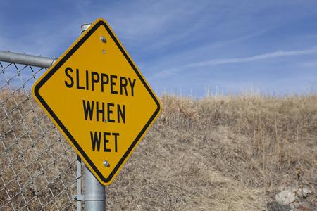 Slippery When Wet yellow and black road signの写真素材