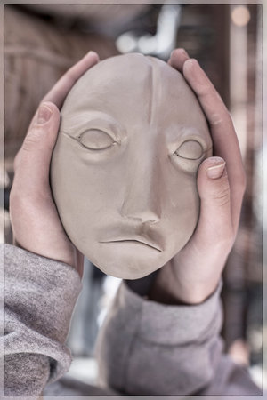 An artist holding a clay head in her hands