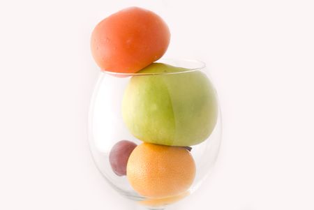 A cup of fresh fruits, including red tomato, green apple, orange, and red grape, on white backgroundの写真素材