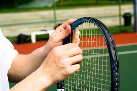 A tennis player is fixing his tennis racket in tennis court.の写真素材