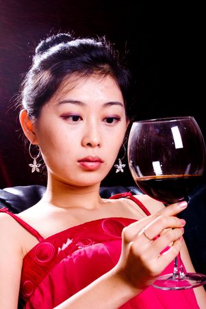 asian female holding goblet with red wineの写真素材