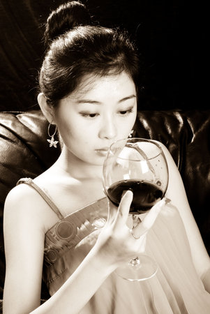 asian female holding goblet with red wineの写真素材