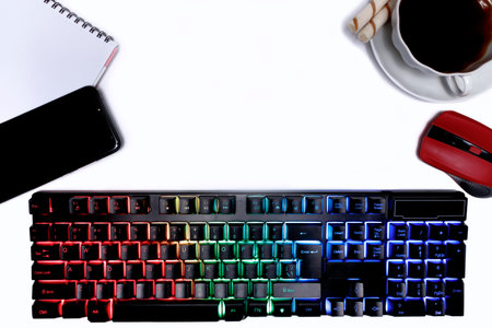 Flat lay composition with a cup of coffee, a glowing keyboard, mouse, smartphone and a notepad on a...